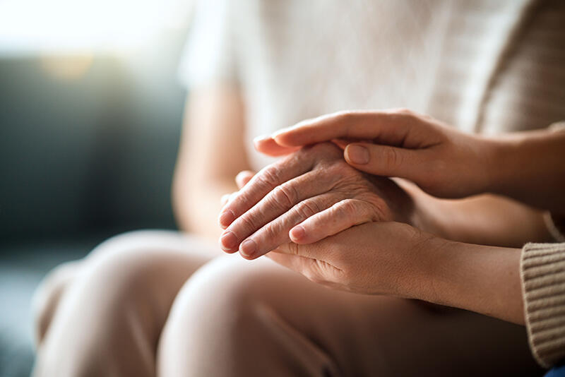 One person rests a hand over another’s, both seated.