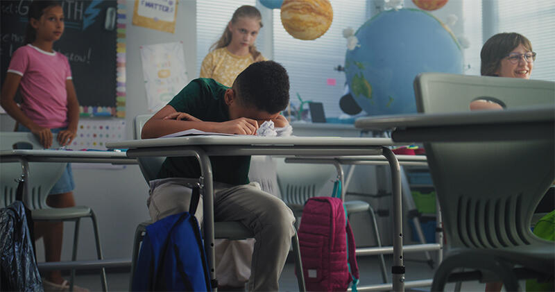 A primary classroom seen from the back, children at their desks.