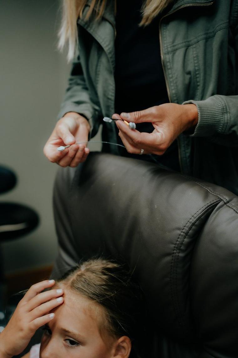 Anna holds two fine sensor leads above a child’s head at the start of a neurofeedback session.