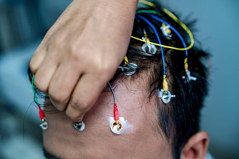 Fine sensor leads being placed in a teenager’s hair before a session.