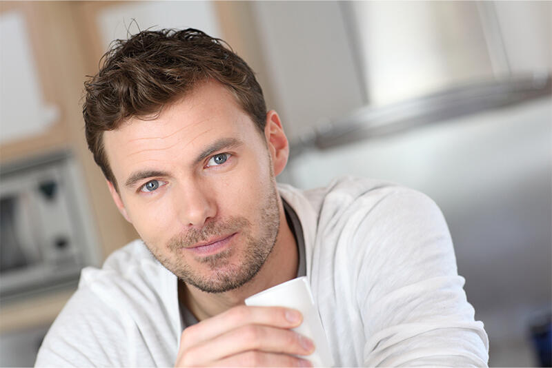 A man sits with a mug, looking calm.